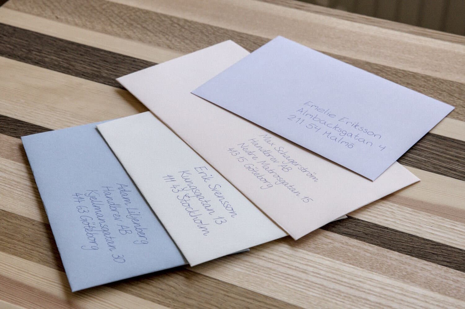 Handwritten envelopes in different colours on a wooden table